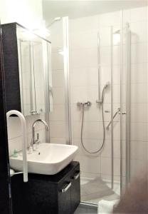 a white bathroom with a sink and a shower at Appartementhäuser Herbert und Walter in Bad Füssing