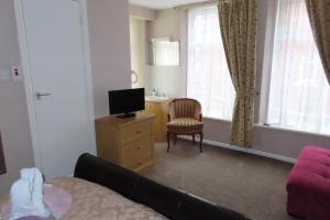 uma sala de estar com um sofá, uma televisão e uma cadeira em The Rowan Hotel em Blackpool