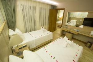 a hotel room with two beds and a mirror at Sundia By Liberty Oludeniz in Oludeniz