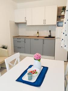 a white kitchen with a table with a vase of flowers at Holiday Home Casa Bianca in Sukošan