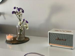 a small speaker next to a vase of flowers and a candle at Refúgio da Falésia in Sesimbra