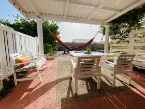 a hammock on a patio with chairs and a table at Tropical Breeze Curaçao in Santa Catharina