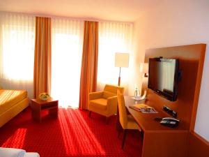 a hotel room with a bed and a desk and a television at Hotel Gasthof Posthalter in Zwiesel