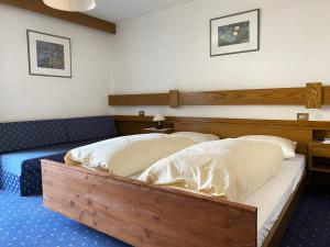 a bedroom with two beds with a wooden headboard at Hotel Friedemann in Rasùn di Sotto