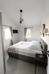 une chambre blanche avec un grand lit et deux fenêtres dans l'établissement Ostseehaus am Naturstrand - Arkonablick, à Varnkevitz