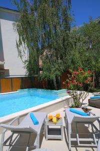 a swimming pool with two chairs and a table next to it at Hotel Alkima in Kotor