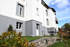 a white house with a stone wall in front of it at Le Chellois appartement La Bresse in La Bresse