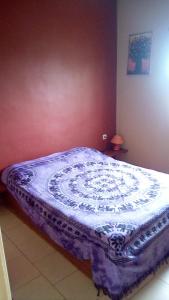 a bed in a bedroom with a purple and white comforter at Auberge Le Baobab in Saly Portudal