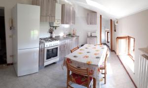 een keuken met een tafel en een witte koelkast bij Appartamento Cielo in Costermano