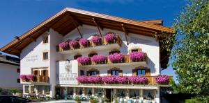 a white building with purple flowers on the balconies at Hotel Tschurtschenthaler in Dobbiaco