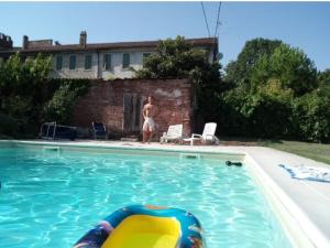 a man is standing next to a swimming pool at La Casa Grande di Corte Italia in Sorga