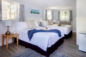 2 camas en una habitación con paredes y ventanas blancas en Sesuit Harbor House, en East Dennis