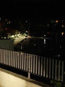 a night view of a harbor with a white fence at House Olivia in Pučišća