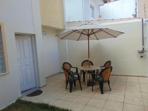 a patio with a table and chairs and an umbrella at Vila Stellino Suítes in São Paulo