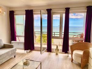 a living room with purple curtains and a view of the ocean at Studio mit Panorama-Meerblick und direkter Strandlage in Scharbeutz in Scharbeutz