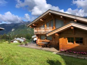 a large wooden house with a deck in a field at Chalet Nanook in Notre-Dame-de-Bellecombe