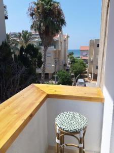 einen Hocker auf einem Balkon mit Stadtblick in der Unterkunft PORT CITY HAIFA - BAT GALIM 25 mtrs from the beach & Rambam in Bat Gallim