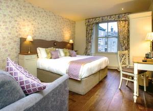 um quarto de hotel com uma cama, um sofá e uma secretária em The Devonshire Grassington em Grassington