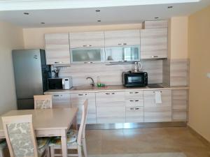 a kitchen with wooden cabinets and a table with a microwave at Golden Dunes Primorsko Apartments in Primorsko