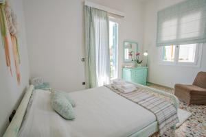 a white bedroom with a bed and a window at Villa Magnolia in Nafplio