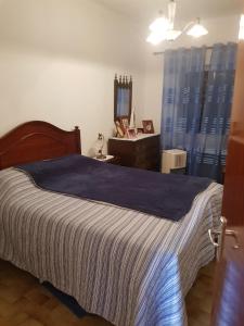 een slaapkamer met een bed met een blauwe deken en een spiegel bij Pérola Achadense Guesthouse in Achada