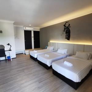 una camera d'albergo con tre letti e una persona appesa al muro di Foresight Hotel a Tawau