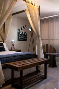 um quarto com uma cama de dossel e um banco de madeira em Pousada Rua de Lazer em Domingos Martins