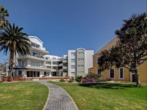 a large white building with palm trees and a walkway at Atlantic Garden Boutique Hotel in Swakopmund