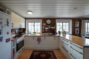 a kitchen with white cabinets and a clock on the wall at Fidjeland 61 in Tjørhom