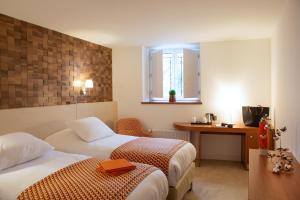 a hotel room with two beds and a desk at Hotel Le Clos De La Vouge in Vougeot