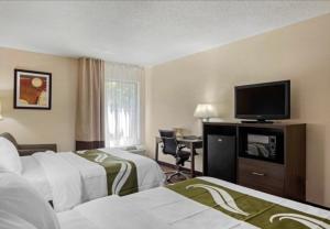a hotel room with two beds and a flat screen tv at Quality Inn High Point - Archdale in Archdale