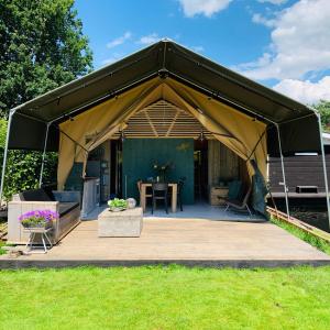 a black tent with a table in a yard at Glamping aan de Plas in Vinkeveen