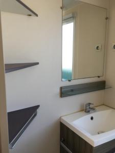 La salle de bains est pourvue d'un lavabo et d'un miroir. dans l'établissement Mobilhome avec vue sur étang, à Bec-de-Mortagne