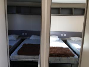 a bedroom with two beds and a mirror at Mobilhome avec vue sur étang in Bec-de-Mortagne