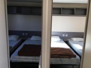 - une chambre avec 2 lits et un miroir dans l'établissement Mobilhome avec vue sur étang, à Bec-de-Mortagne