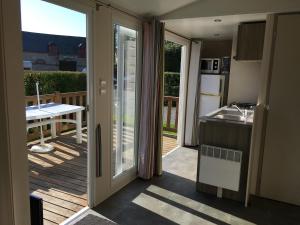 Une porte ouverte s'ouvre sur une cuisine dotée d'un balcon. dans l'établissement Mobilhome avec vue sur étang, à Bec-de-Mortagne