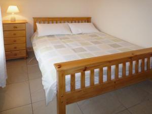 a bedroom with a bed with a wooden frame and a dresser at Timmys Cottage Heir Island by Trident Holiday Homes in Skibbereen