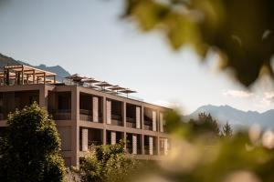 un bâtiment avec des fenêtres et des montagnes en arrière-plan dans l'établissement Sonnen Resort, à Naturno