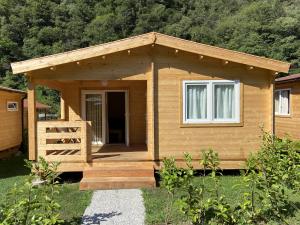 a small wooden cabin with a porch and a door at Camping Piccolo Paradiso in Avegno