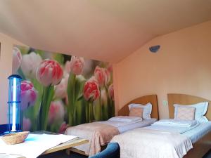 two beds in a room with a mural of pink tulips at Pensiunea Paloma 3 stele Brasov in Braşov