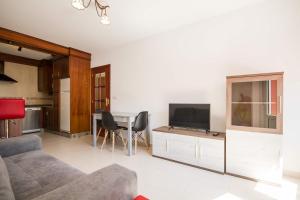 ein Wohnzimmer mit einem Sofa und einem Tisch mit einem TV in der Unterkunft Los Molinos, con terraza in Corcubión