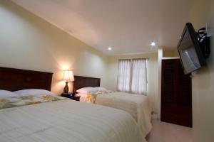 a bedroom with two beds and a flat screen tv at Rainbow Hotel in Caye Caulker