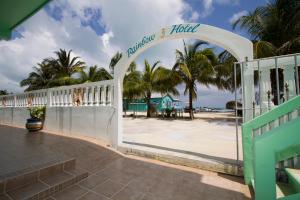a white fence with palm trees in the background at Rainbow Hotel in Caye Caulker