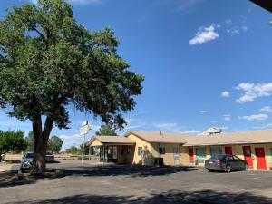 a parking lot in front of a building with a tree at Lariat Motel in Moriarty