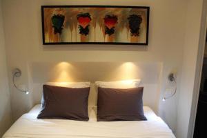 a bed with two pillows and a painting above it at Burdigala Homes - Les Apparts de la Course in Bordeaux