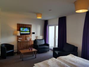 a hotel room with a bed and chairs and a tv at Vakantiehotel Der Brabander in Winterberg