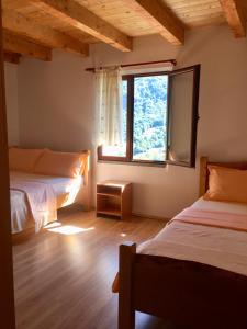 a bedroom with two beds and a large window at Guest house PANORAMA in Theth