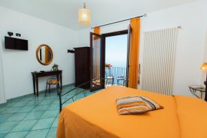 a bedroom with a bed with an orange blanket and a balcony at Roccia Fiorita in Furore