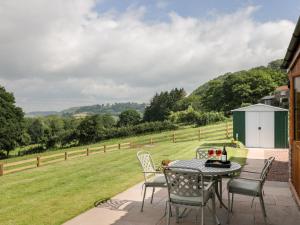 een patio met een tafel en stoelen en een veld bij The Comfy Cow in Usk