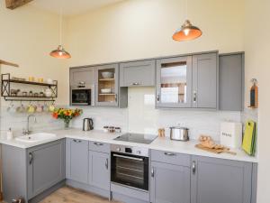 a kitchen with gray cabinets and a sink at The Comfy Cow in Usk